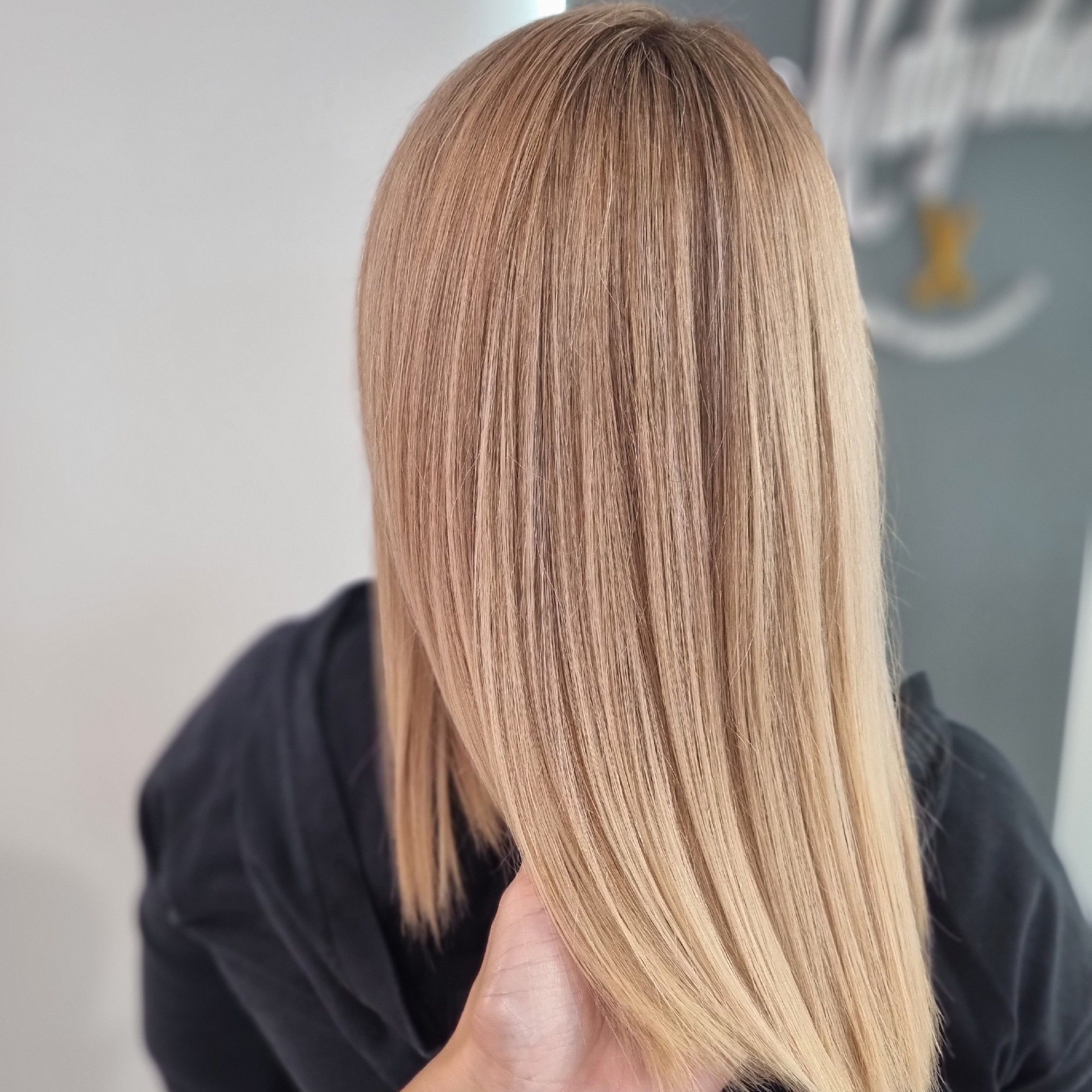 Długie blond włosy z rozjaśnionym balejażem ułożone w miękkie fale